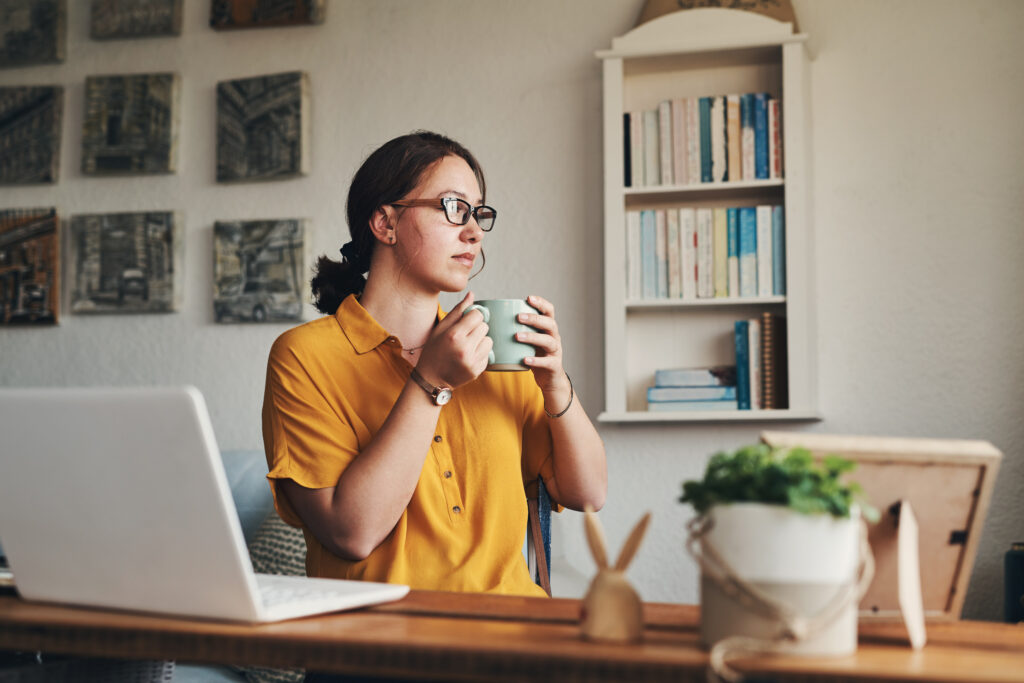 Grab your coffee and get it done. a young woman having coffee and looking thoughtful while working from home